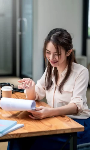 Happy young Asian businesswoman to work holding documents at the office.